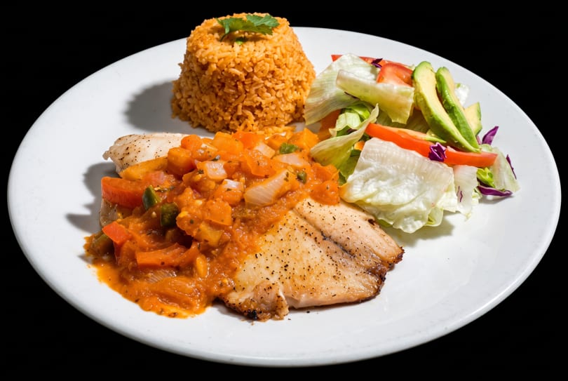 Grilled fish with tomato-vegetable sauce, seasoned rice, and a fresh salad with avocado.