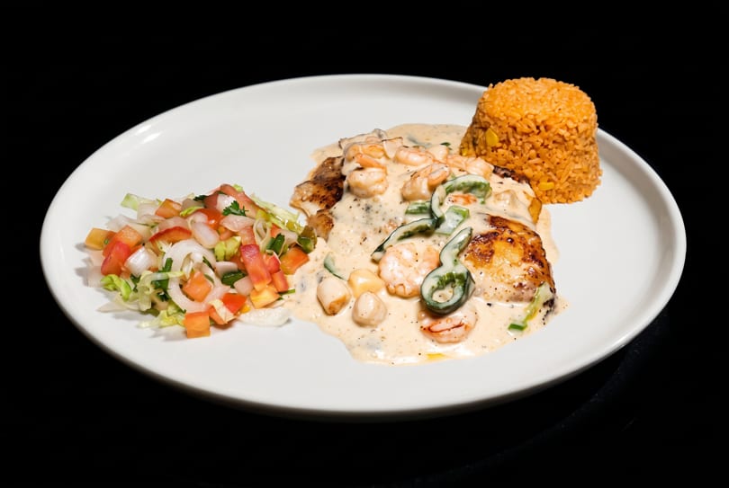 Grilled fish with creamy shrimp, scallop, and pepper sauce, Mexican rice, and fresh pico de gallo.
